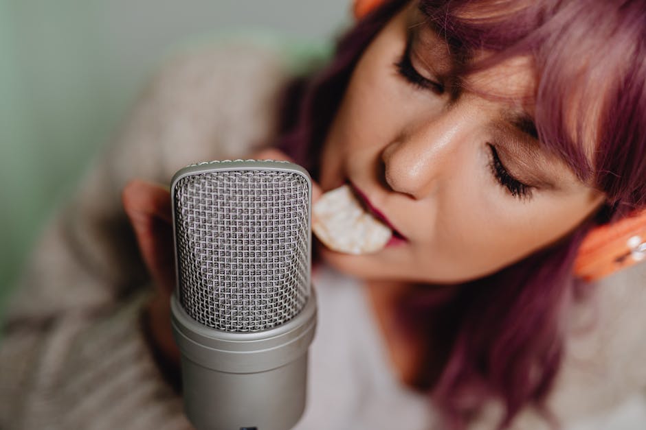 Woman with headphones recording ASMR, eating a chip near a microphone.