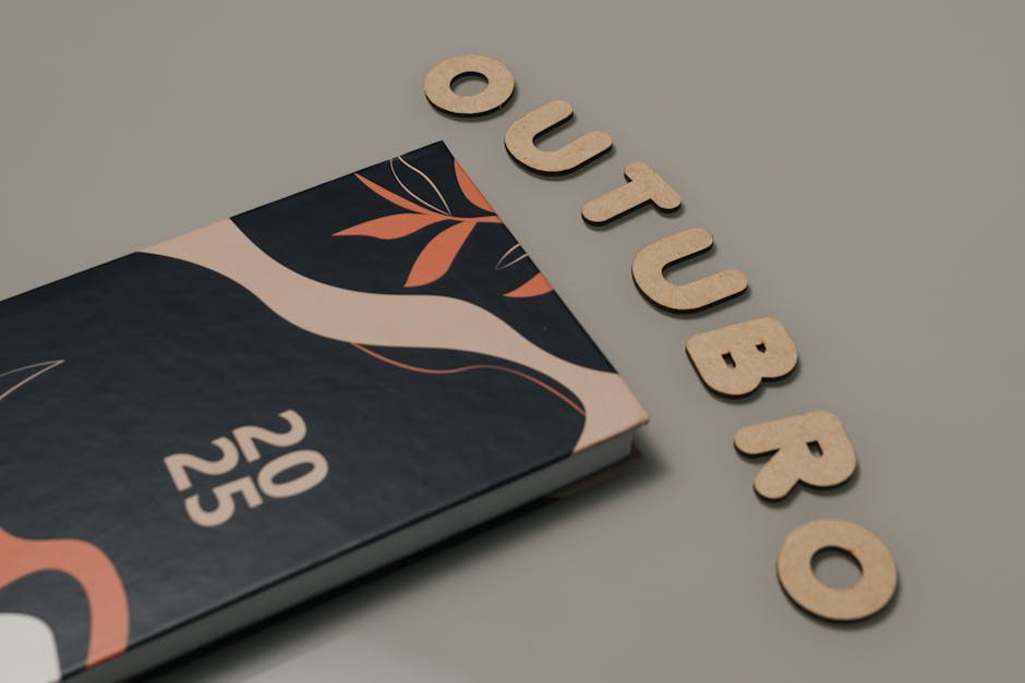 Minimalist flat lay featuring a 2025 planner and cut-out letters spelling 'OUTUBRO'.