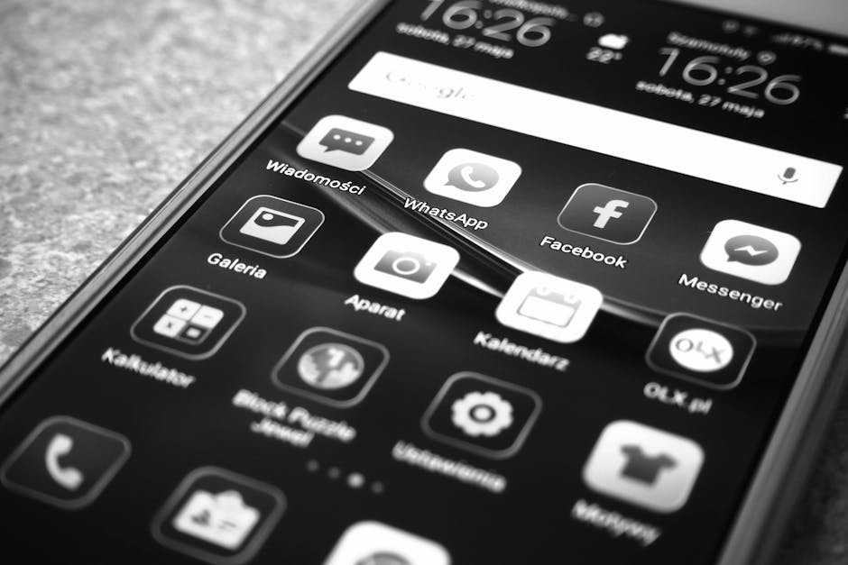 Black and white photo of smartphone showing popular app icons like Facebook and WhatsApp.