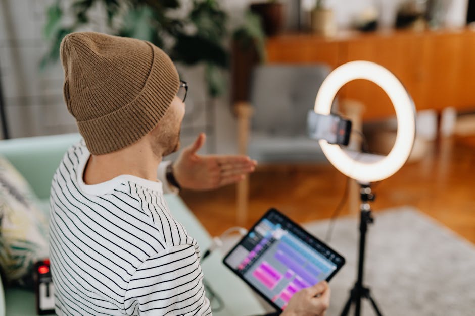 Adult male recording podcast using tablet and cellphone with ring light indoors