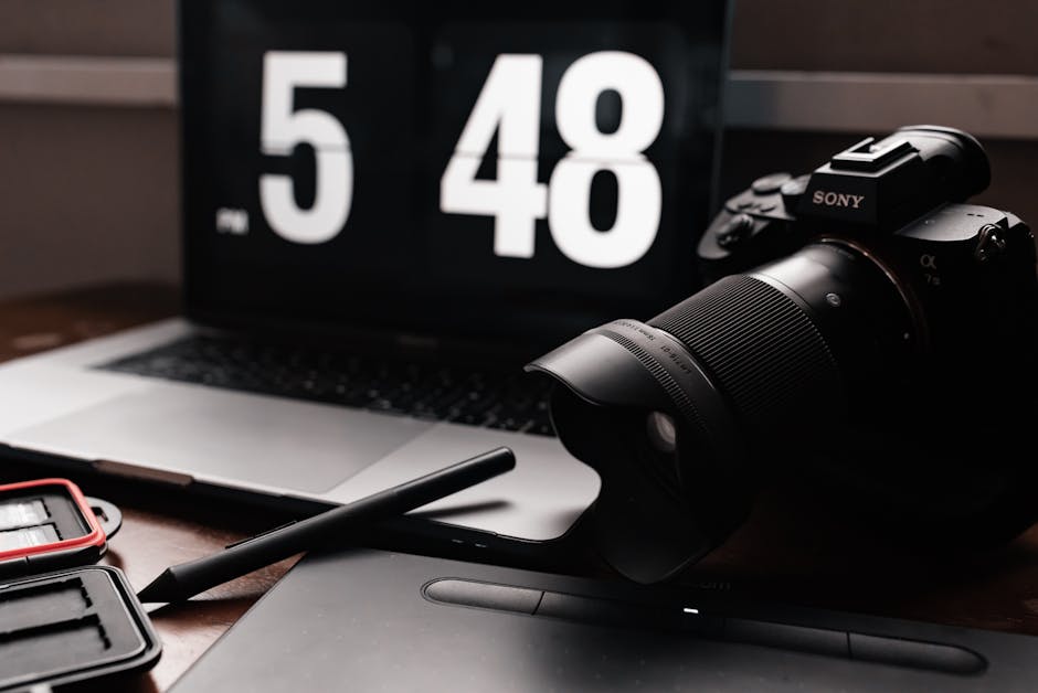 A stylish setup featuring a camera, laptop, and digital pen on a desk.